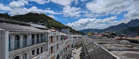 A street with traditional buildings, a clear sky, and mountains in the background.