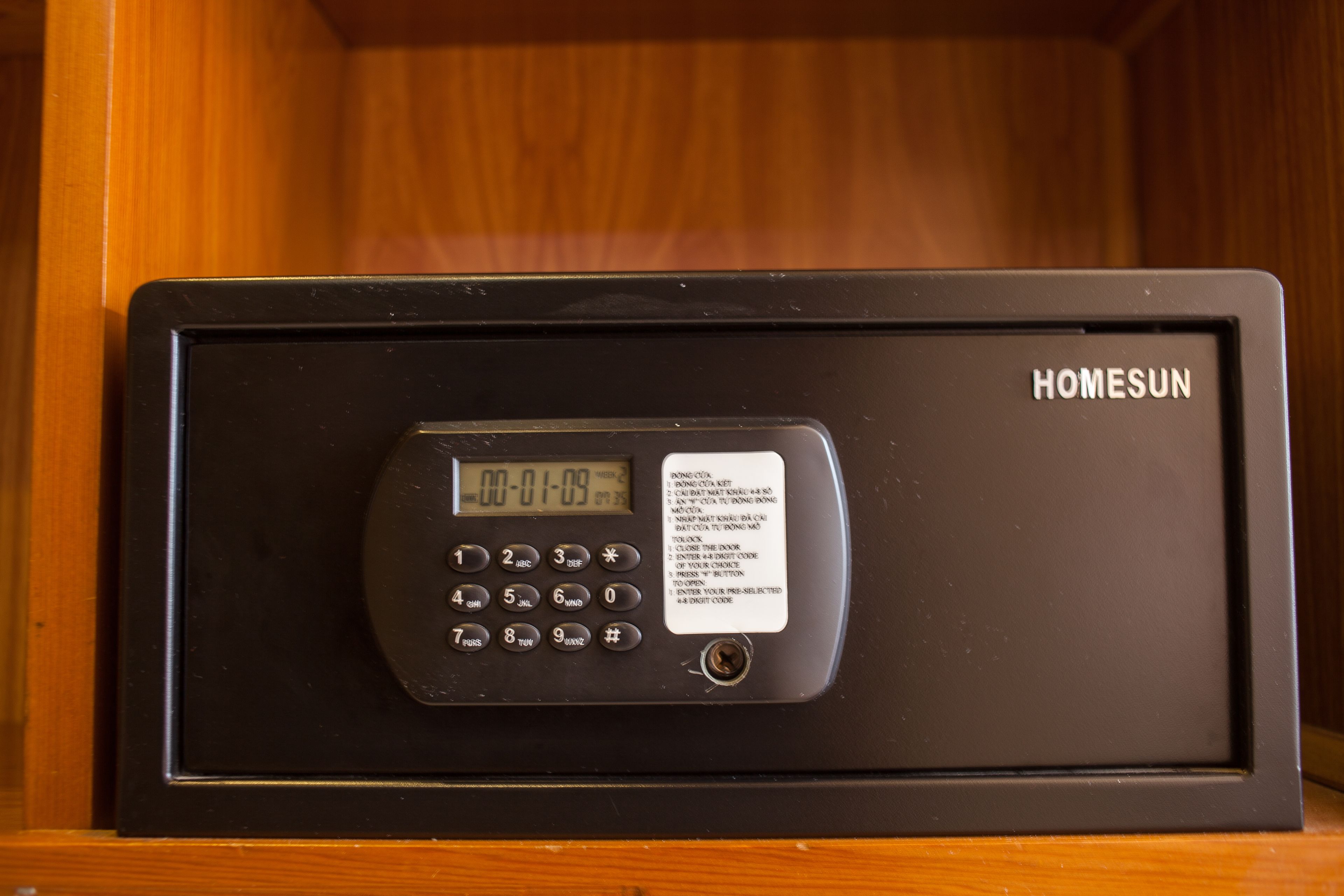 Un panel de control de seguridad negro con pantalla digital, etiquetado como 'HOMESUN'.