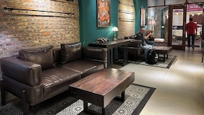 A modern lounge area with leather sofas, a wooden coffee table, and a brick wall. - Sapa Centre Hotel (Sa Pa)