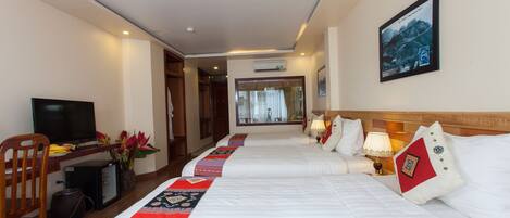 A hotel room with two beds, a desk with a television, a chair, and a window with curtains.