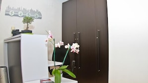 Un espacio de oficina moderno con un escritorio, una orquídea en maceta y un cuadro de arte con vistas a la ciudad.
