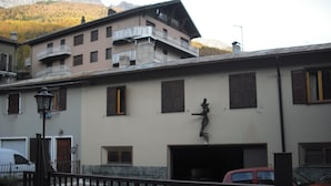 A building with a balcony, a statue, and a garage. - Albergo Gufo Depandance (Bormio)