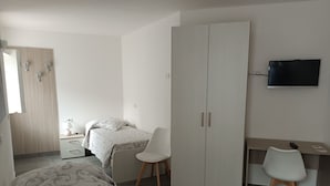 A bedroom with a bed, a desk, a chair, a wardrobe, and a TV. - Albergo Gufo Depandance (Bormio)