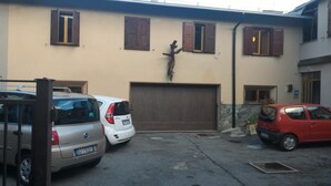 A building with a garage door, a statue, and three parked cars. - Albergo Gufo Depandance (Bormio)