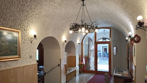 A hallway with a rustic stone ceiling, wooden paneling, and a chandelier. There are arched doorways leading to other rooms. - Albergo Gufo Depandance (Bormio)