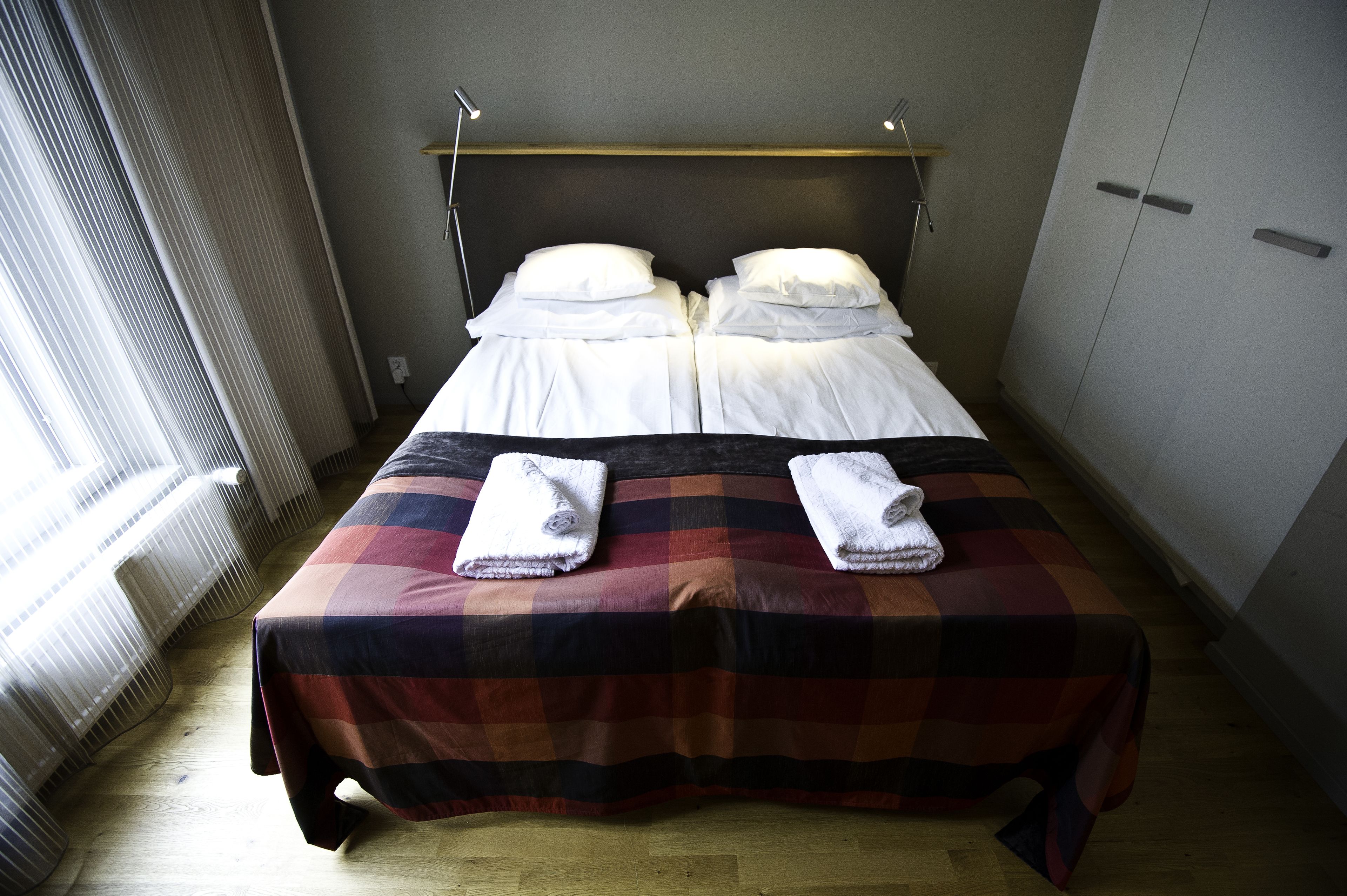 Ein Doppelbett mit kariertem Überwurf und zwei Handtüchern daneben.