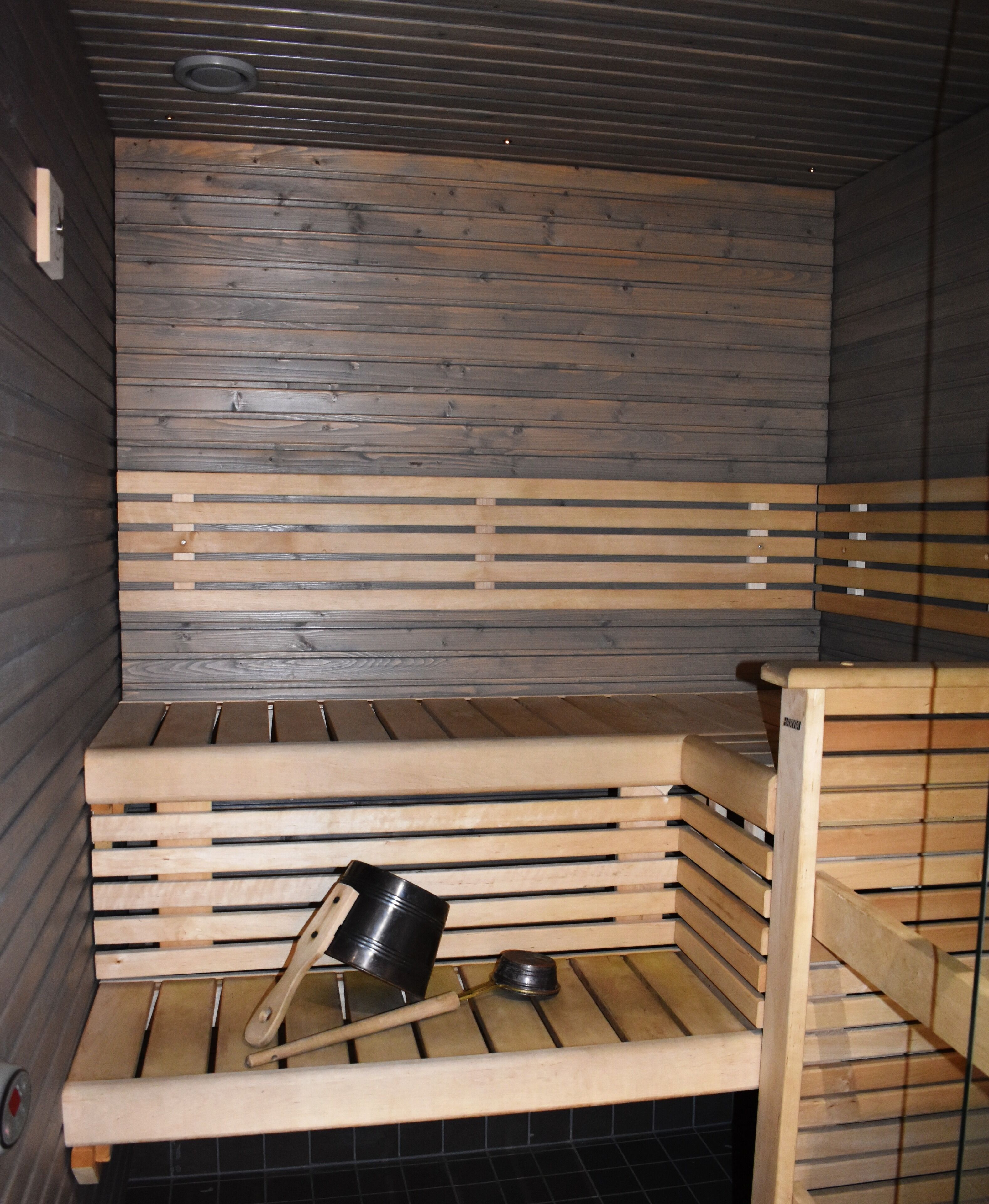 Eine Sauna mit Holzbänken und einem Metallkübel.