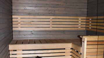 Eine Sauna mit Holzbänken und einem Metallkübel.