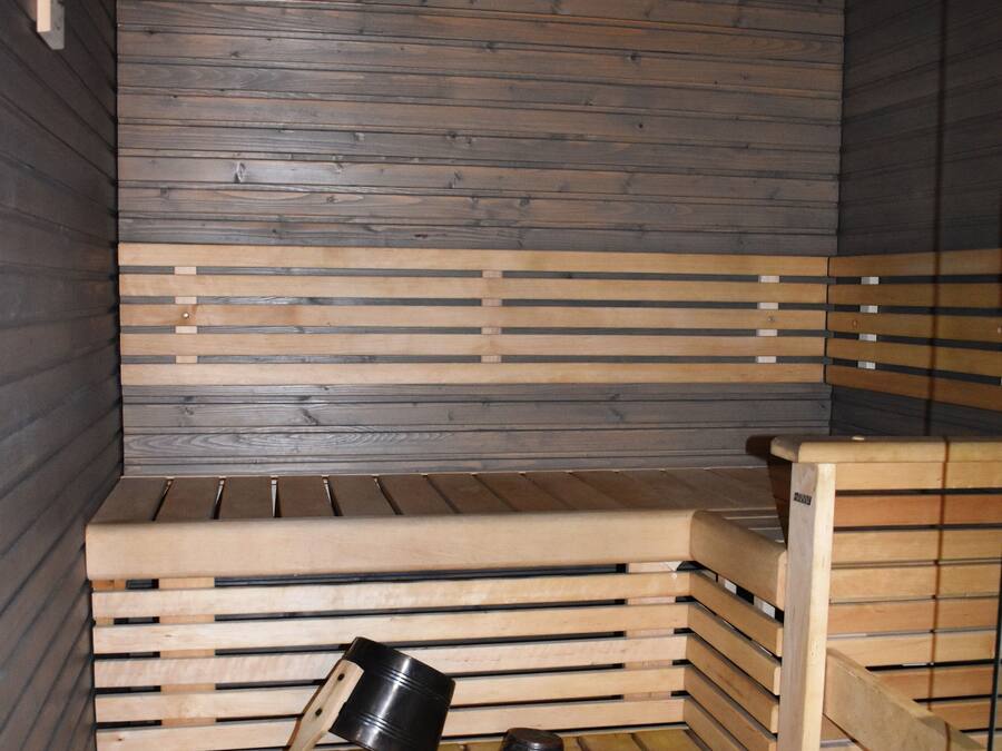 Eine Sauna mit Holzbänken und einem Metallkübel.