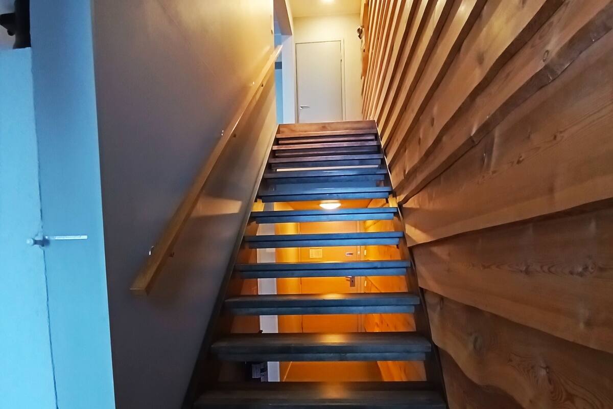 A wooden staircase with a modern design, leading to a door at the top.