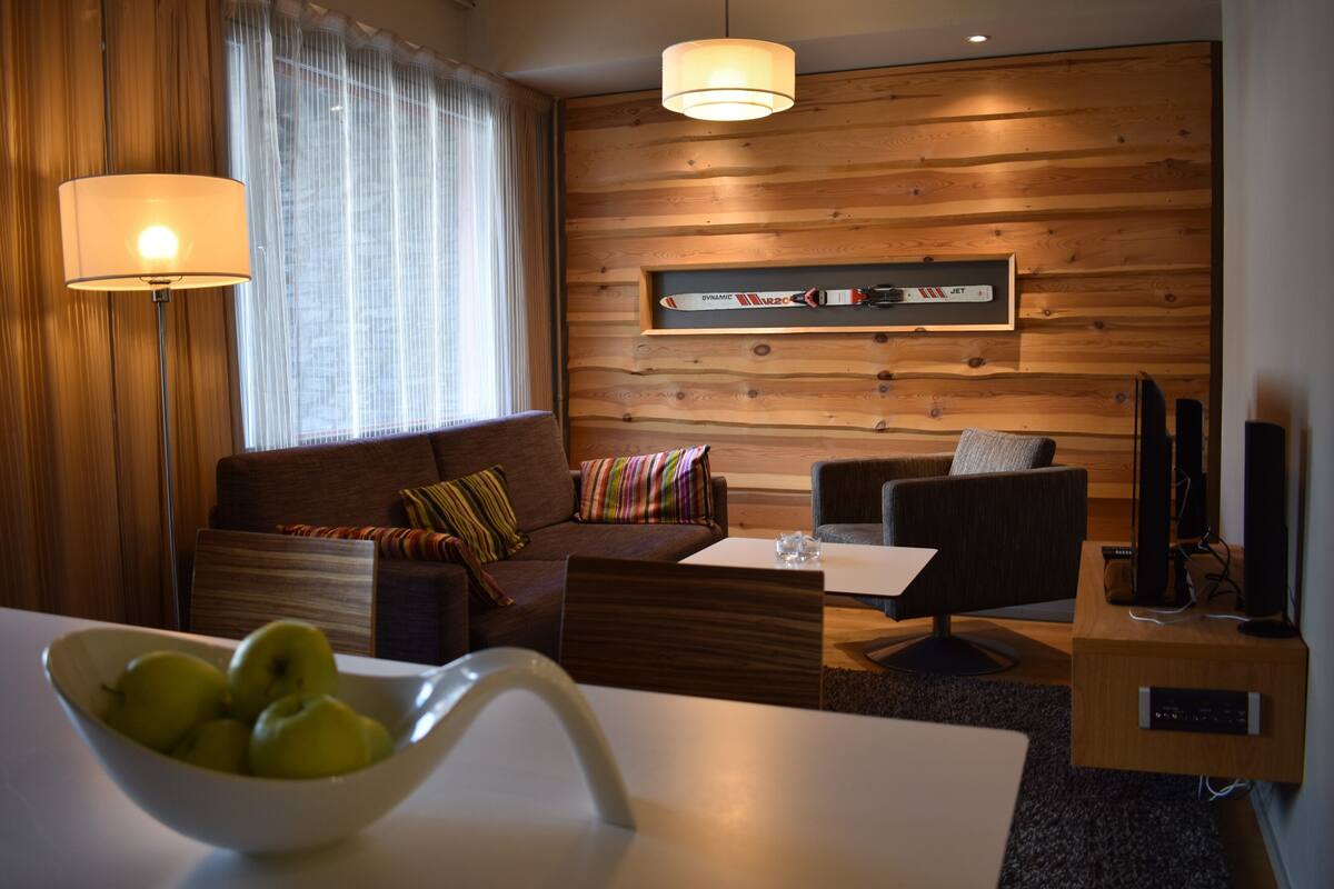 A modern living room with a wooden wall, a sofa, a coffee table, and a TV stand.