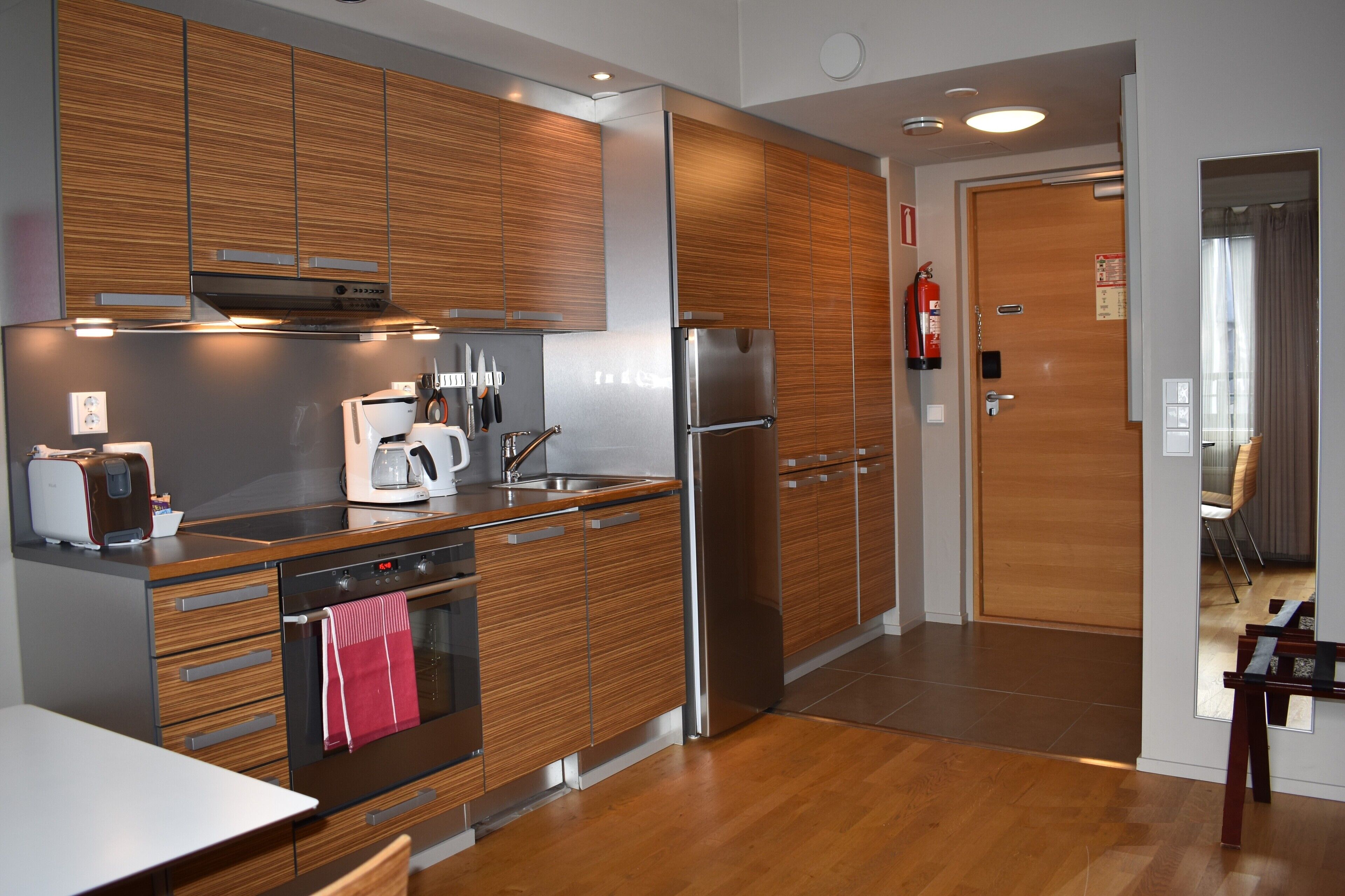 A modern kitchen with wooden cabinets, stainless steel appliances, and a wooden dining table.