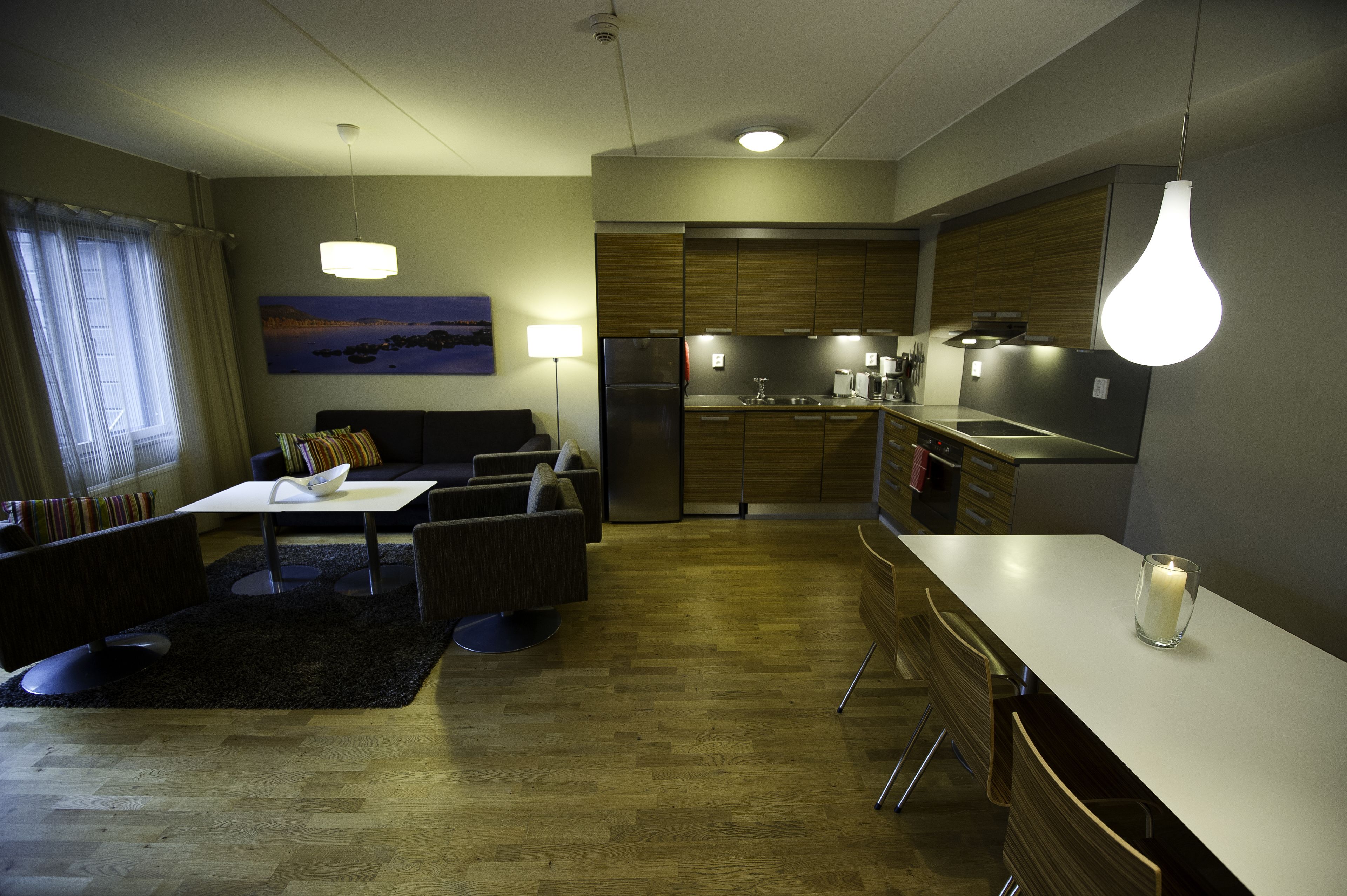 A modern kitchen with a refrigerator, stove, and dining area with a table and chairs.