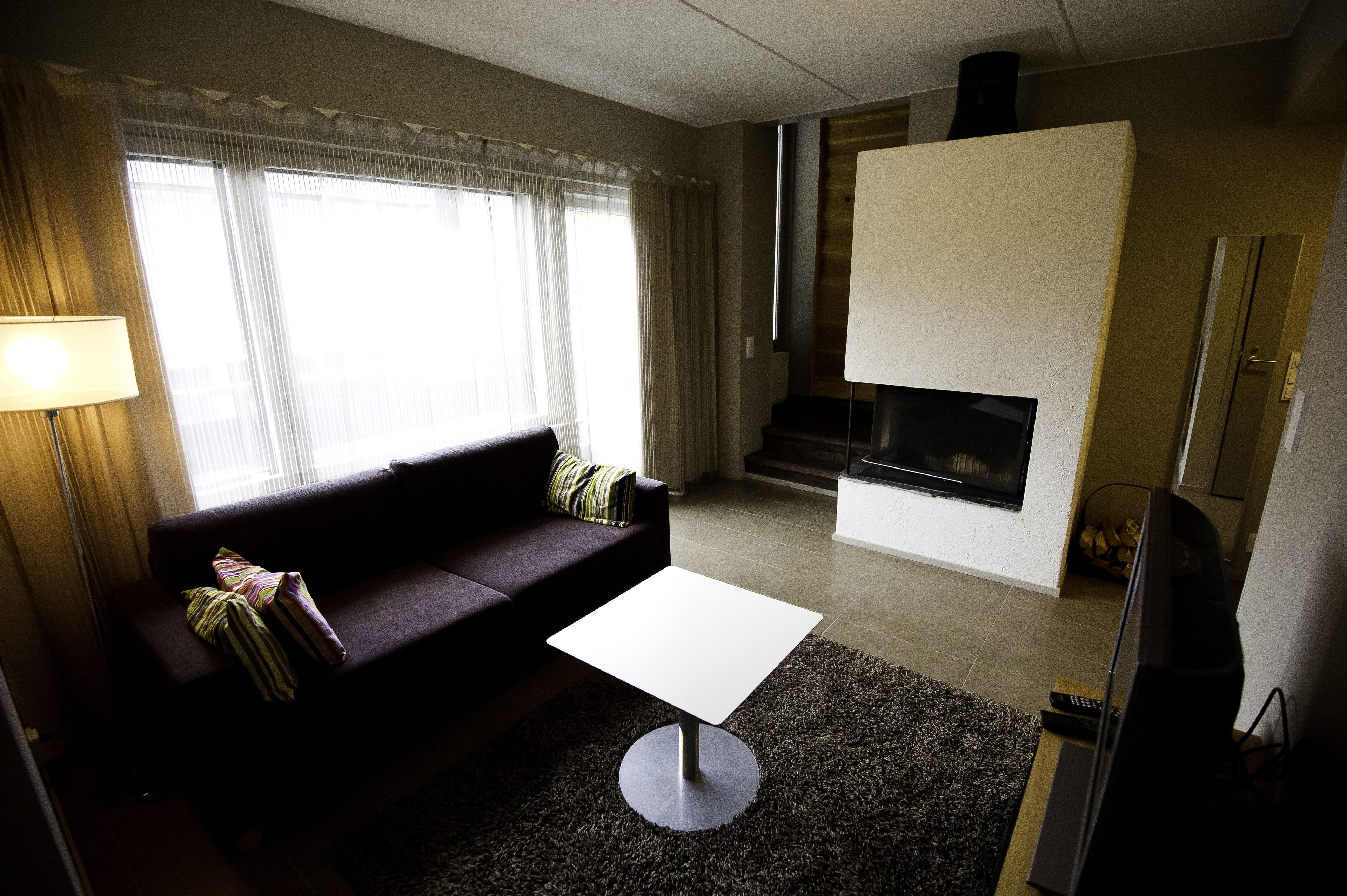 A living room with a sofa, a coffee table, a fireplace, and a television.