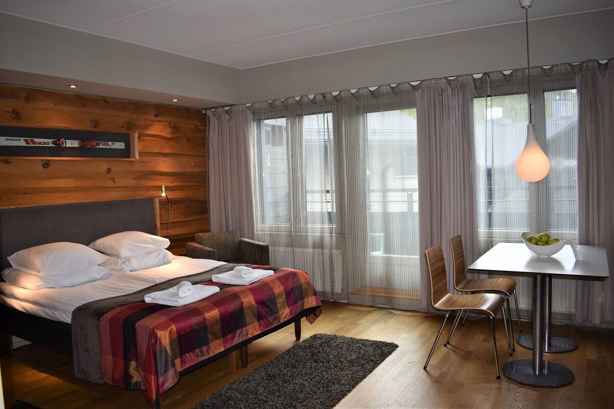 A modern hotel room with a bed, a dining table, and a chair.