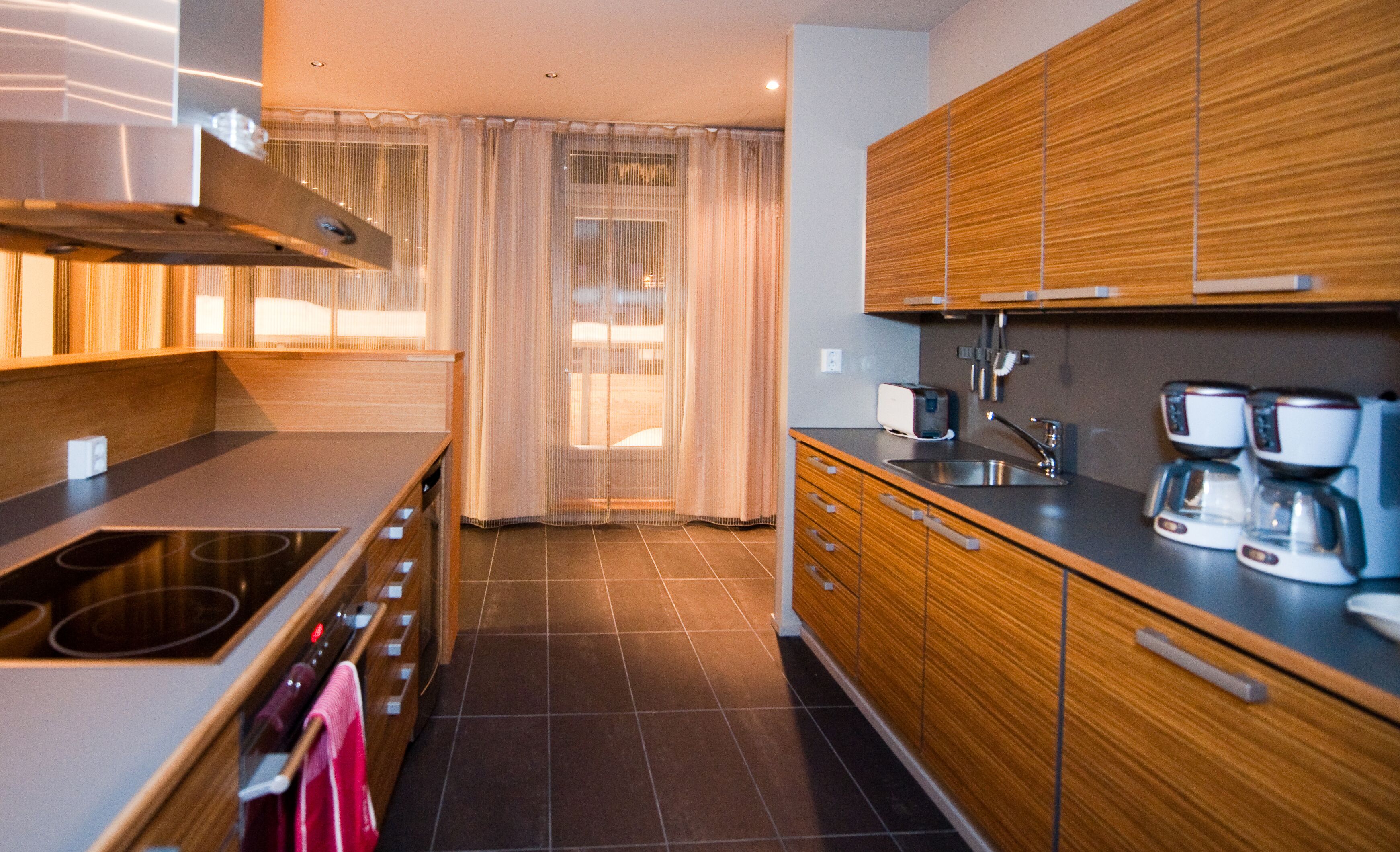 A modern kitchen with wooden cabinets, a stainless steel sink, and a coffee maker.