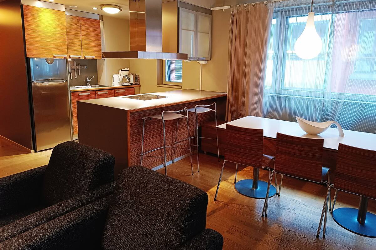 A compact kitchen with a refrigerator, stove, and bar stools.