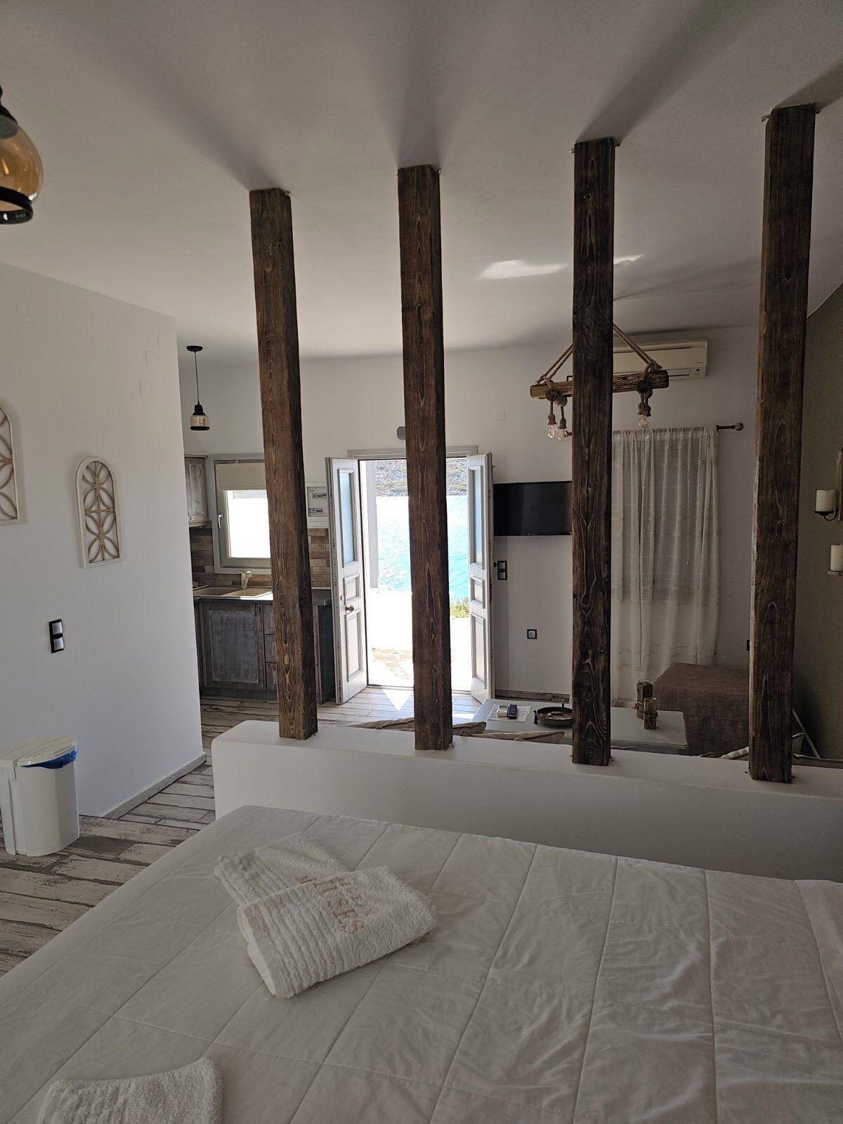 A bedroom with a large bed, wooden beams, a television, and a view of the outside.