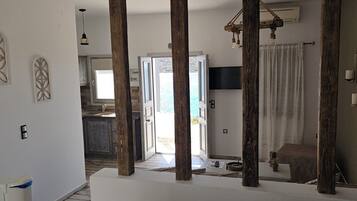 A bedroom with a large bed, wooden beams, a television, and a view of the outside.
