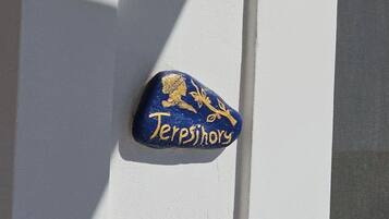 A blue plaque with gold lettering on a white wall, reading "Terpsihory".
