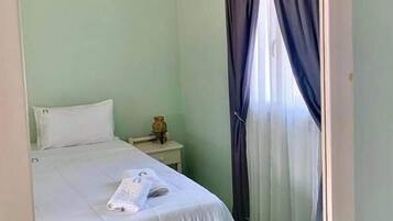 A bedroom with a bed, a nightstand, and a mirror.