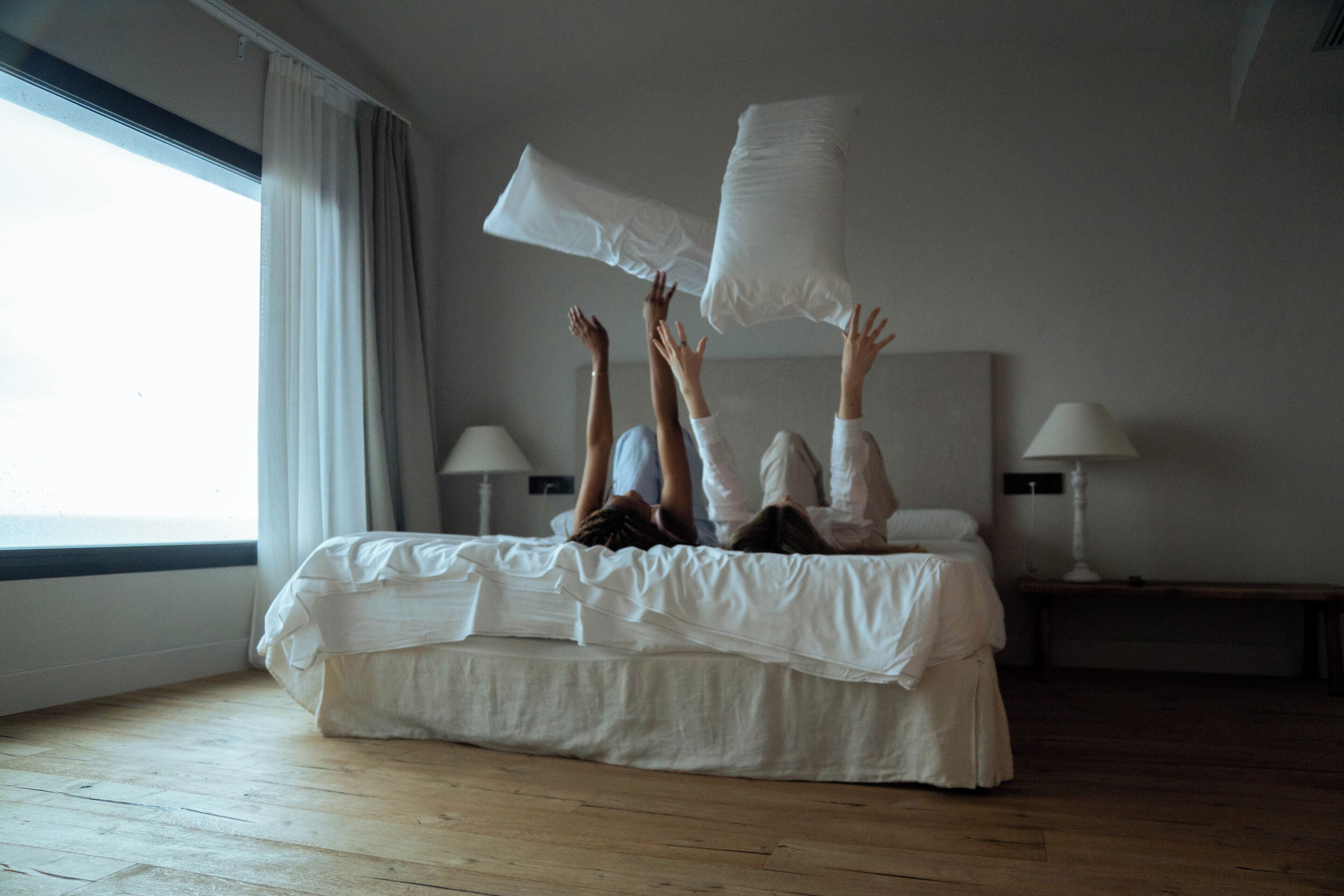 A bedroom with a large bed, two bedside lamps, and a window with curtains.