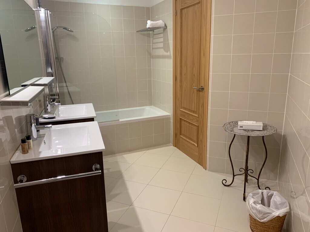 Un baño con ducha, bañera, lavamanos y tocador.
