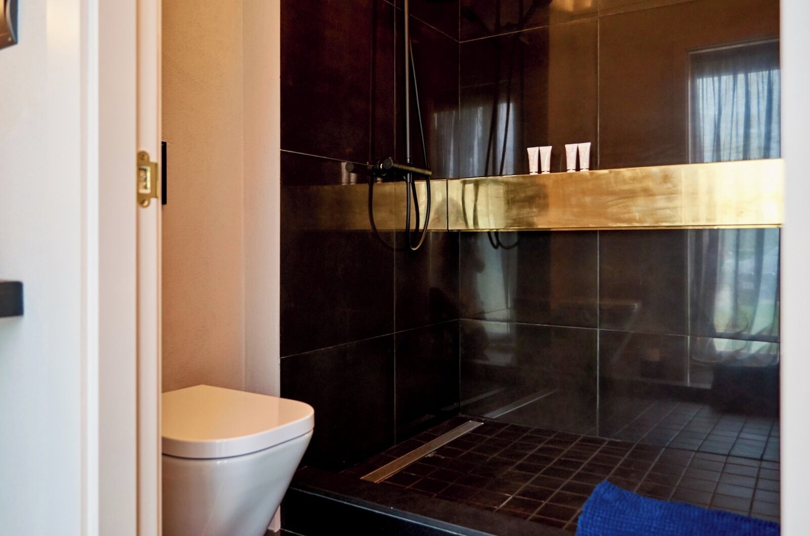 A modern bathroom with a toilet, a shower area, and a glass-enclosed vanity.
