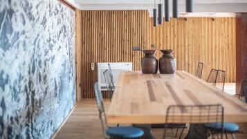 Un salón de conferencias con una mesa de madera, sillas azules y dos jarrones grandes.