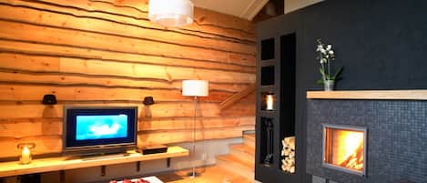 Una sala de estar moderna con una pared de madera, una chimenea, un televisor y un sofá.