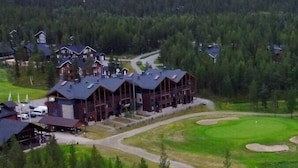 Un albergue con varias cabañas, un campo de golf y un paisaje boscoso.