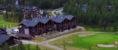 A lodge with multiple cabins, a golf course, and a forested backdrop.