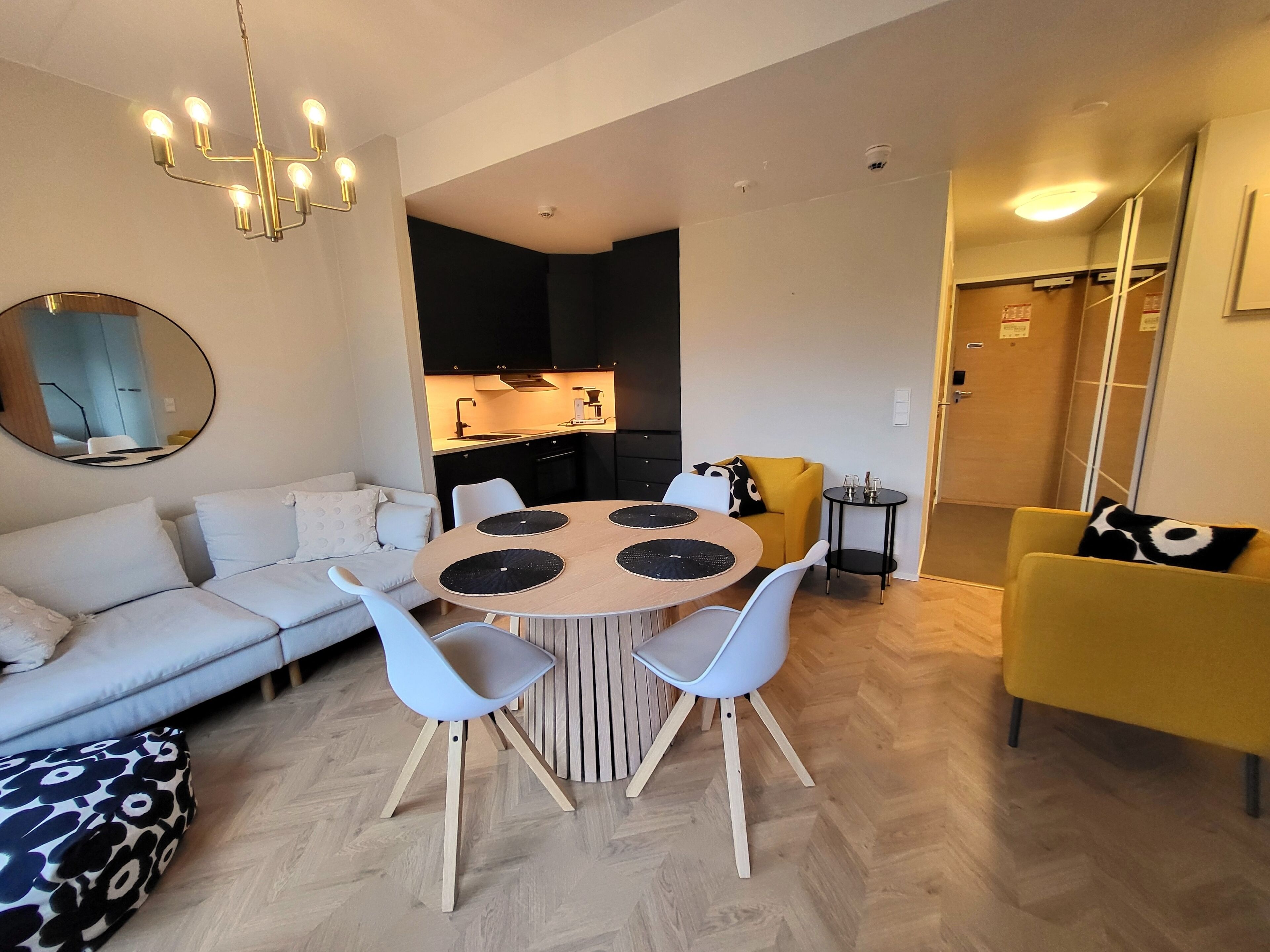 Un salon moderne avec une table ronde en bois, des chaises blanches, un canapé et un fauteuil jaune.