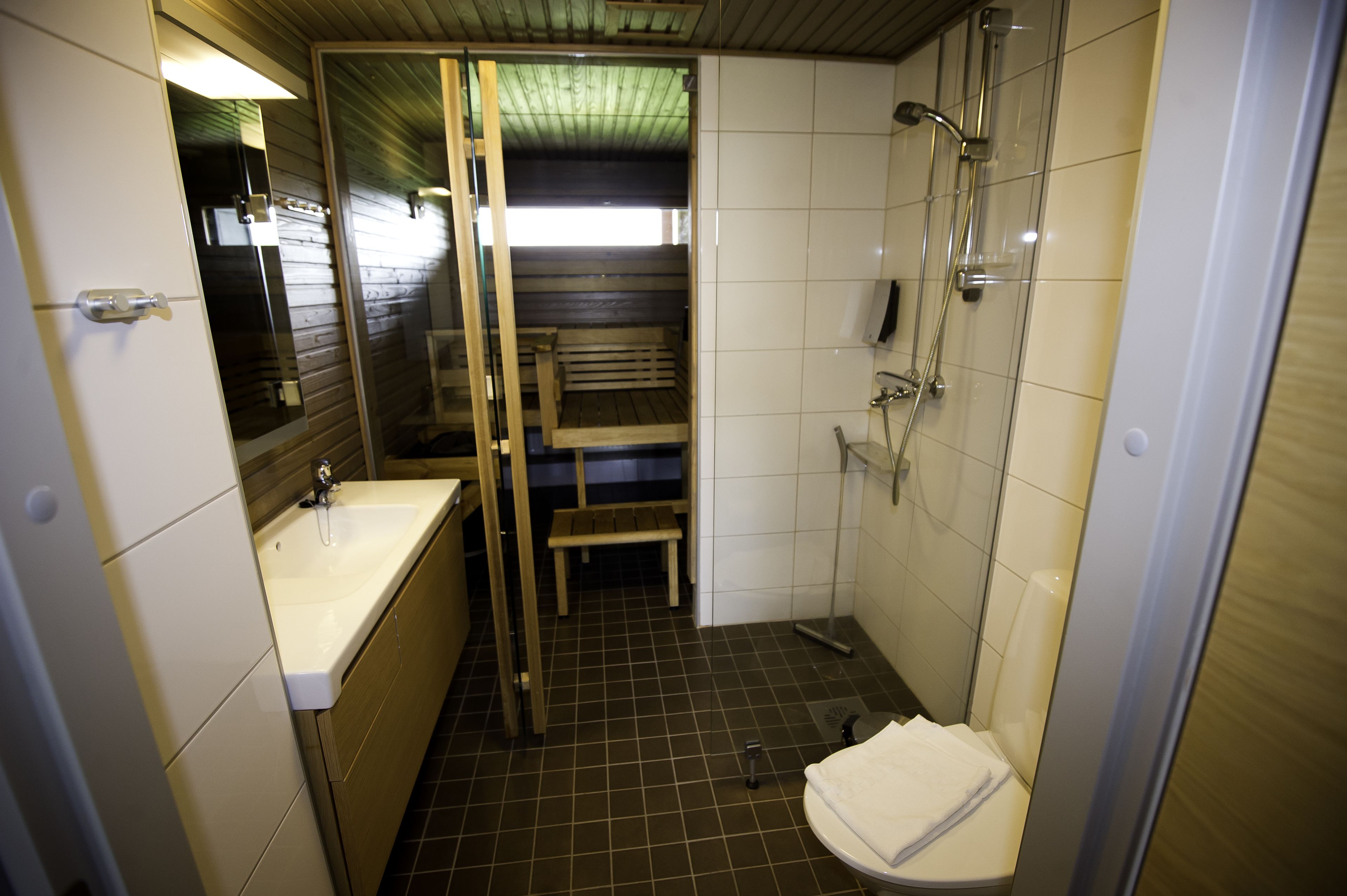 A compact bathroom with a sink, toilet, and shower.