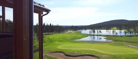 En vy över en golfbana med en sjö, träd och ett kuperat landskap.