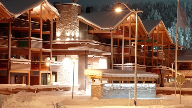 Una cabaña de varios pisos con balcones de madera y una chimenea de piedra.