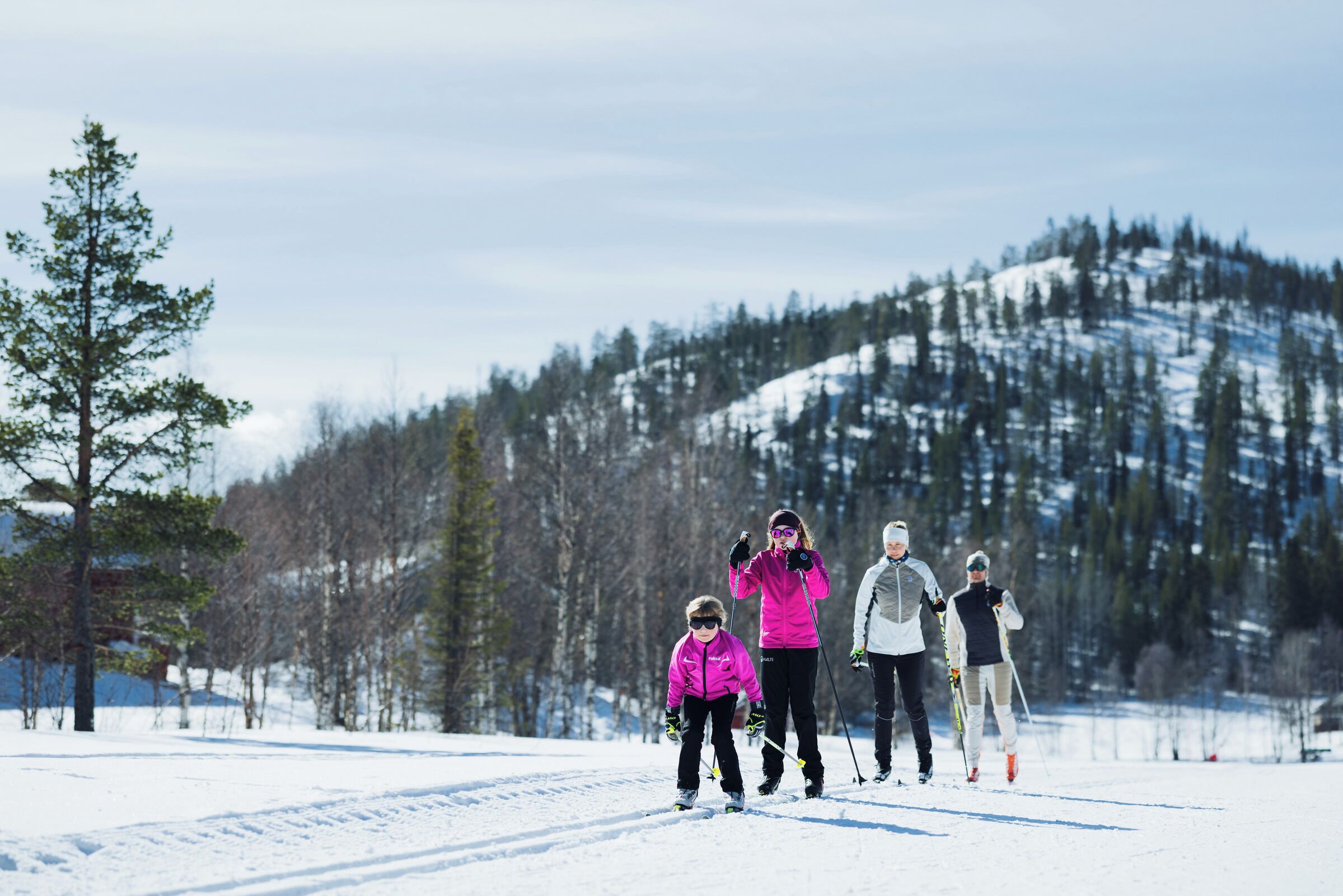 Un paysage enneigé où l’on voit une famille se promener sur un sentier.