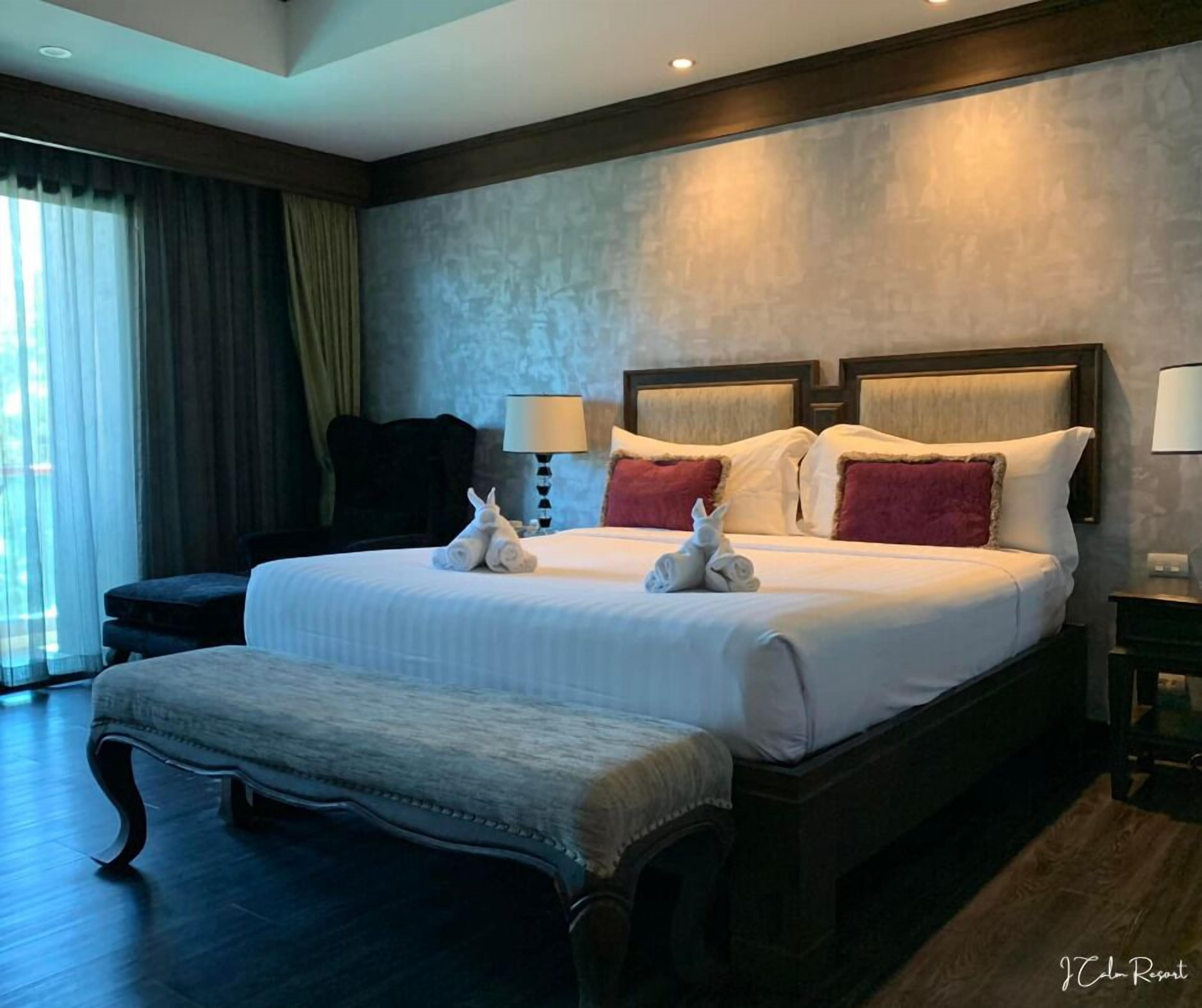 Una cama grande con cabecera de madera, un banco y dos lámparas.
