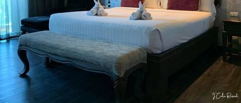 Una cama grande con cabecera de madera, un banco y dos lámparas.
