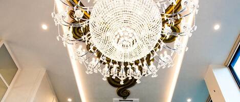 A lobby with a large chandelier, a decorative wall with a circular pattern, and a reception desk.