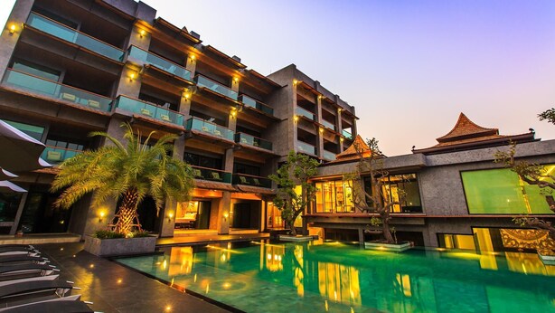 A multi-story hotel with a swimming pool, outdoor seating, and a traditional-style building with a tiled roof. - I Calm Resort (Cha-am)