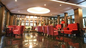 A lobby with a polished marble floor, red upholstered seating, and a central light fixture. - I Calm Resort (Cha-am)