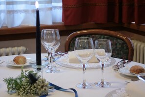 A dining table set with fine china, glassware, and a candle. - Hotel Larice Bianco (Bormio)