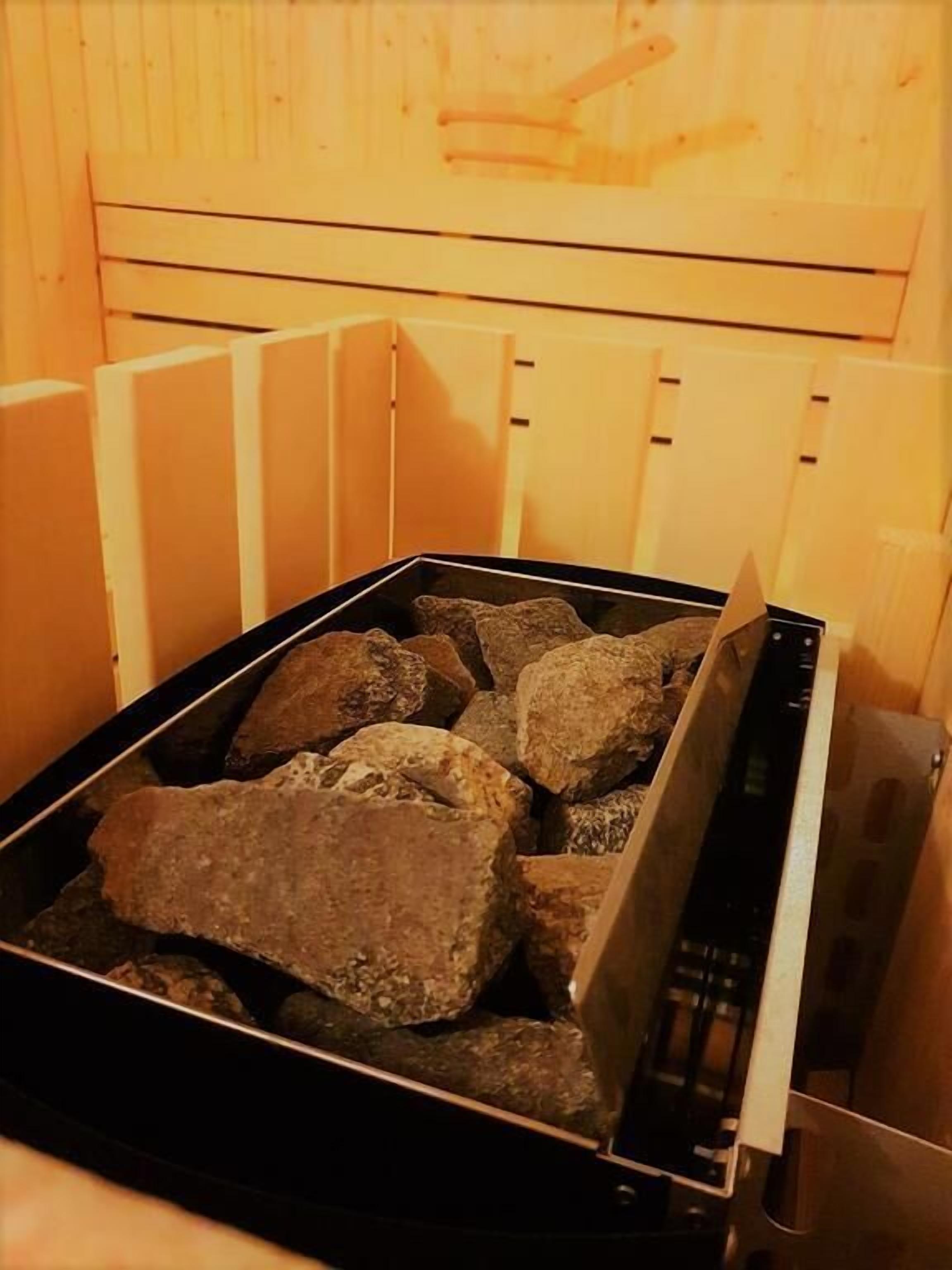 A sauna with a black heating element and several large rocks inside.