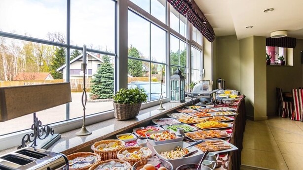 A buffet setup with various food items and a toaster, near large windows with a view of houses and trees. - Willa Klodzko - Zacisze (Klodzko Miasto)