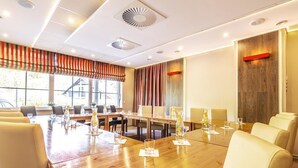 A conference room with a long wooden table, multiple chairs, and a large window with a view of a building outside. - Willa Klodzko - Zacisze (Klodzko Miasto)