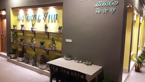 A hotel entrance with a reception desk, a phone number, and a sign with the name 'De Genz Inn'. - De Benz Inn (Malacca City)