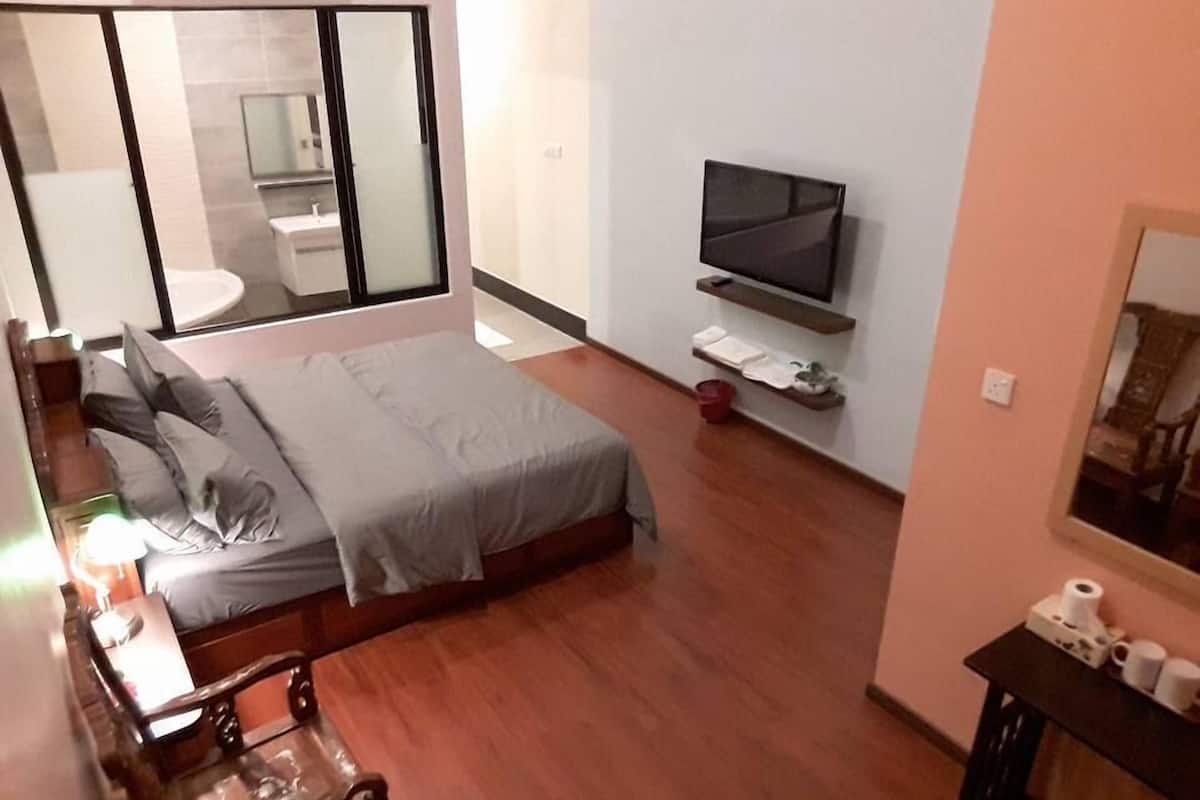 Un dormitorio con una cama, televisor, mesita de noche con artículos de aseo y un espejo.
