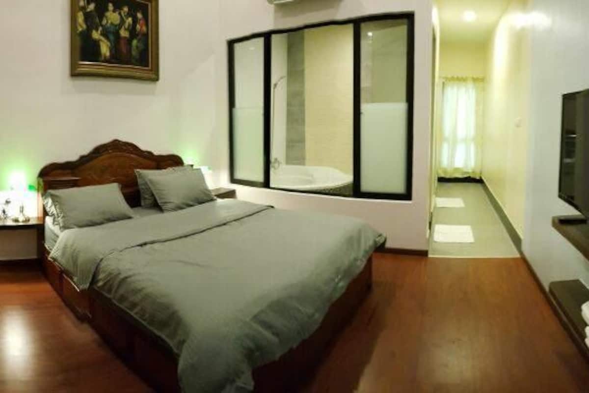 Un dormitorio con una cama, un televisor, un escritorio con lámpara y una silla.