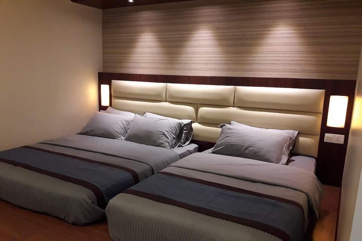 Una cama doble con cabecera y dos mesitas de noche, cada una con una lámpara.